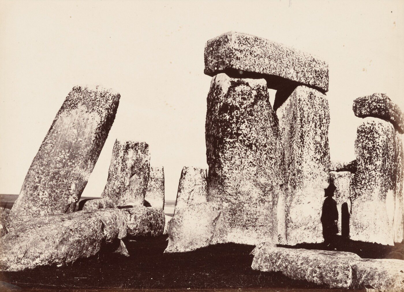A sepia photograph of tall weathered stone uprights capped by a stone lintel on open ground.